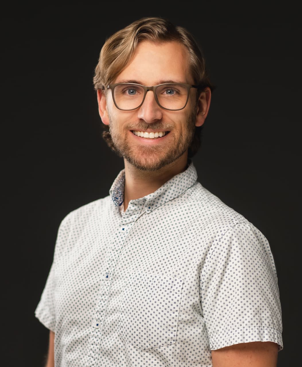 Kyle Haugland smiling in a collared shirt and glasses